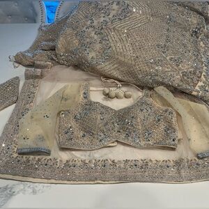 Heavy champagne color bridal lengha with mirror work and zircon stone work